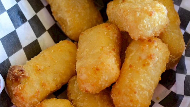 Crispy golden mozzarella-like sticks in a basket with a creamy dipping sauce, perfect for dipping and tasting great.